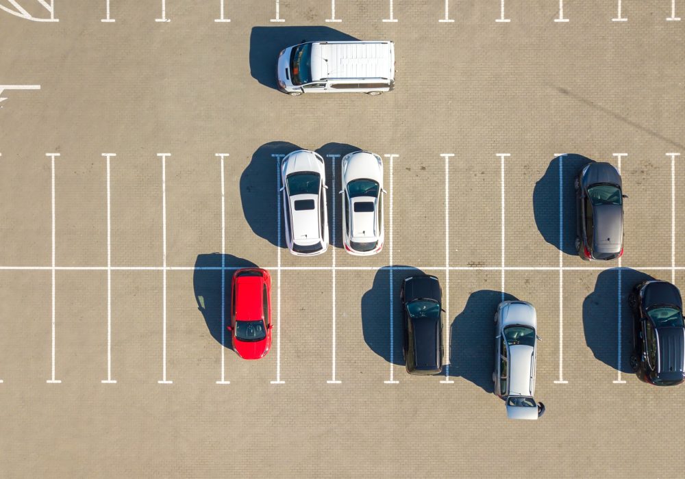 Aerial view of many colorful cars parked on parking lot with lines and markings for parking places