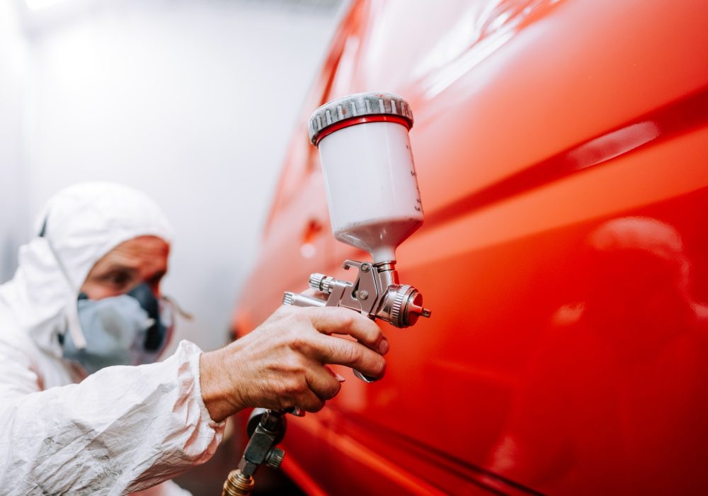 orker painting a car in a special painting box, wearing a full body costume