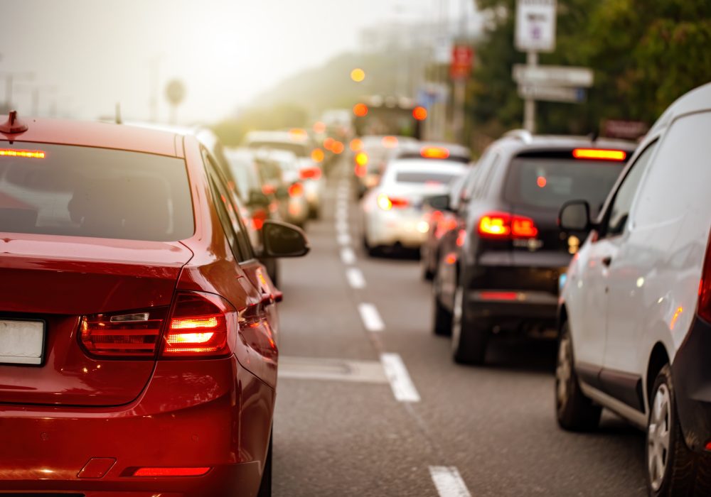 Traffic jam in a city with long queue of cars waiting on a road at sunset