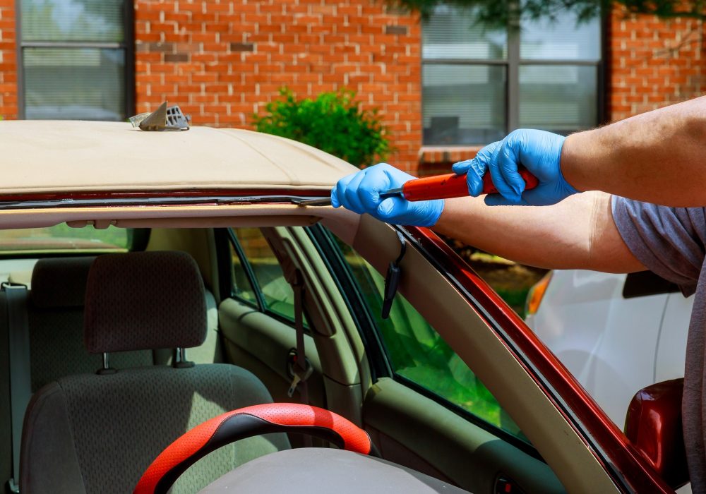 Workers removing glazing car replacement crack broken windscreen car in the car service